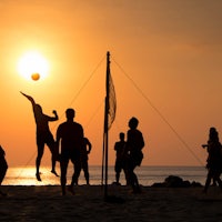 a group of people playing volleyball on the beach