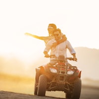 a man and woman riding an atv in the desert