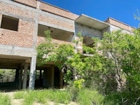 an abandoned building in the middle of a grassy area