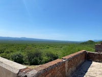 a view from the top of a stone wall overlooking a green area