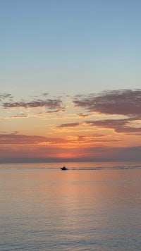 a boat sails across the ocean at sunset