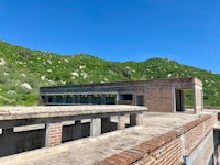 an old building on top of a hill with mountains in the background