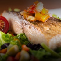 a plate of fish and vegetables on a white plate